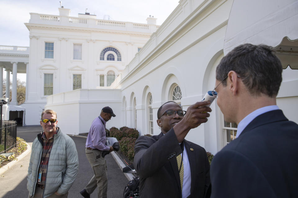 A member of the media, right, gets their temperature taken by member of the White House physicians office, over concerns about the coronavirus outside the James Brady Briefing Room at the White House, Saturday, March 14, 2020, in Washington. The White House announced Saturday that it is now conducting temperature checks on anyone who is in close contact with President Donald Trump and Vice President Mike Pence. The vast majority of people recover from the new coronavirus. According to the World Health Organization, most people recover in about two to six weeks, depending on the severity of the illness.(AP Photo/Alex Brandon)