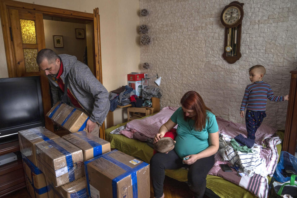 FILE - Internally displaced from Kyiv Dr. Maxim Motsya with his family takes boxes filled with medical aid to send to soldiers on the frontlines, at an apartment given to them by a family member, in Lviv, western Ukraine, on April 3, 2022. When Russian forces two months ago launched a military campaign against infrastructure in Ukraine, it opened an urgent second front far from the contact line: along power lines, water mains, and heating systems, and in places like homes, schools, offices and churches. (AP Photo/Nariman El-Mofty, File)