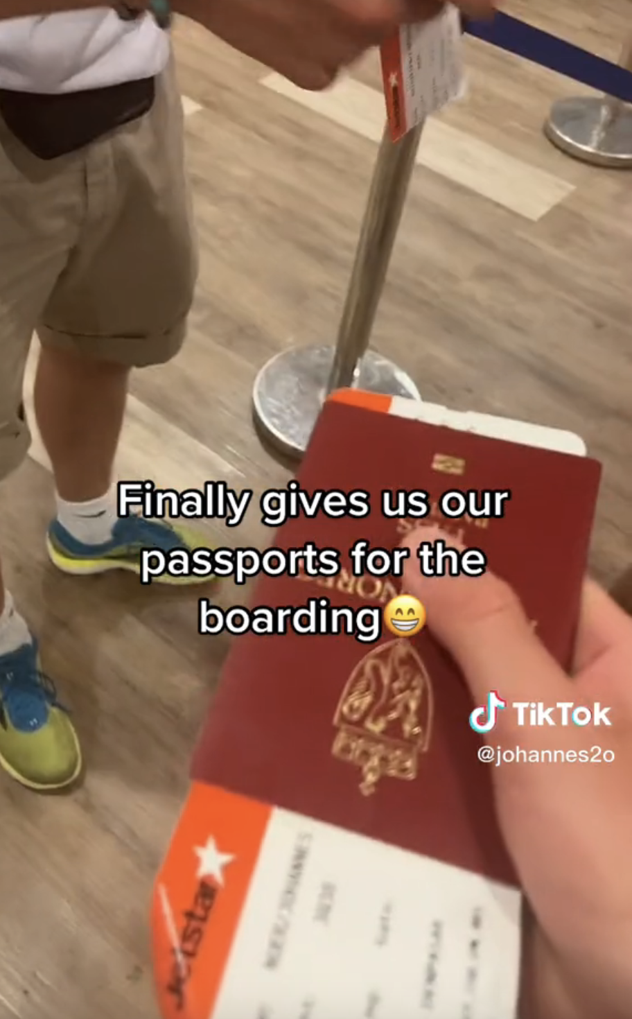 Close-up of hand holding passport with caption "Finally gives us our passports for the boarding" with smile emoji