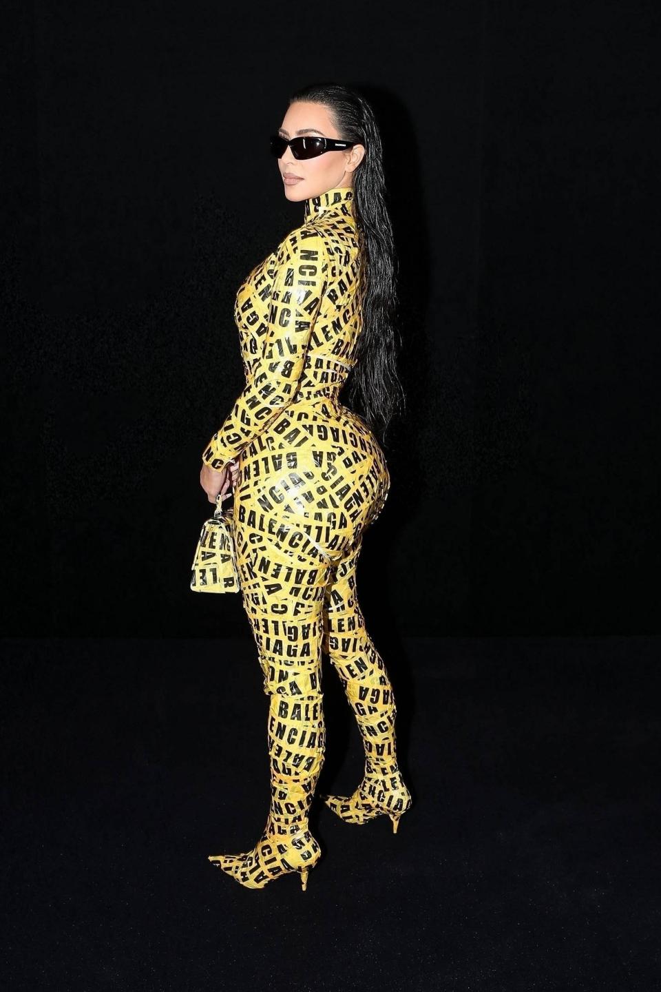 Kim stands while posing in her caution tape dress