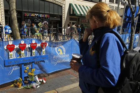 A woman pauses in front of a memorial for the victims of the 2013 Boston Marathon bombings at the site of the first bomb blast in Boston, Massachusetts April 20, 2014. REUTERS/Brian Snyder