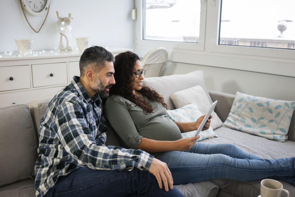 A pregnant couple sits on a couch