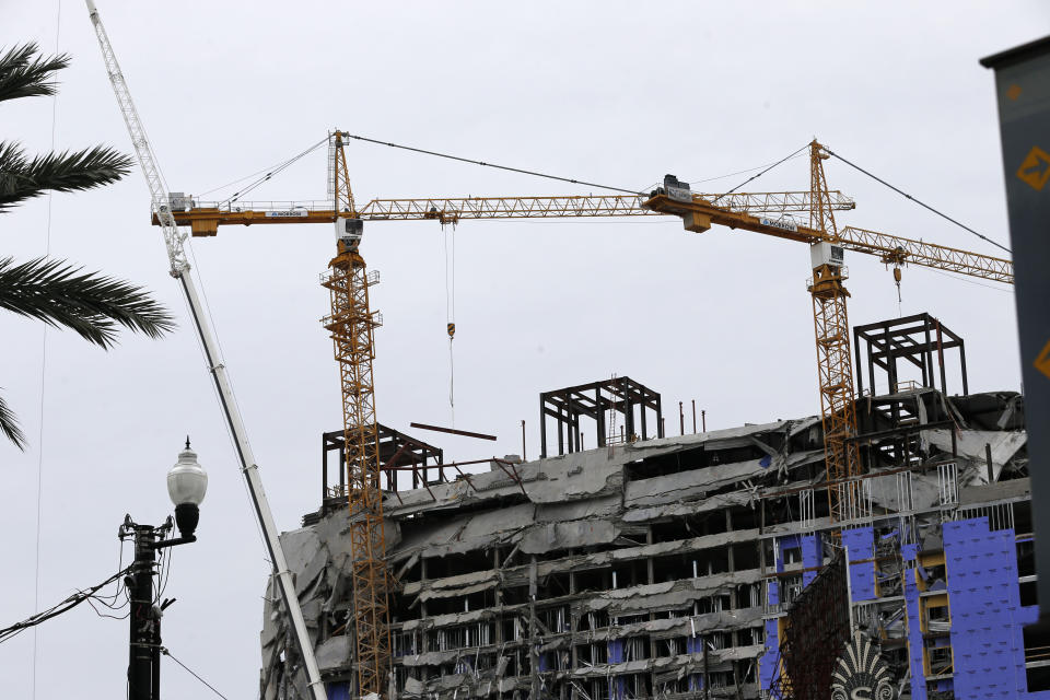 Two unstable cranes loom over the construction of a Hard Rock Hotel, Thursday, Oct. 17, 2019, in New Orleans. The 18-story hotel project that was under construction collapsed last Saturday, killing three workers. Two bodies remain in the wreckage. Authorities say explosives will be strategically placed on the two unstable construction cranes in hopes of bringing them down with a series of small controlled blasts ahead of approaching tropical weather. (AP Photo/Gerald Herbert)