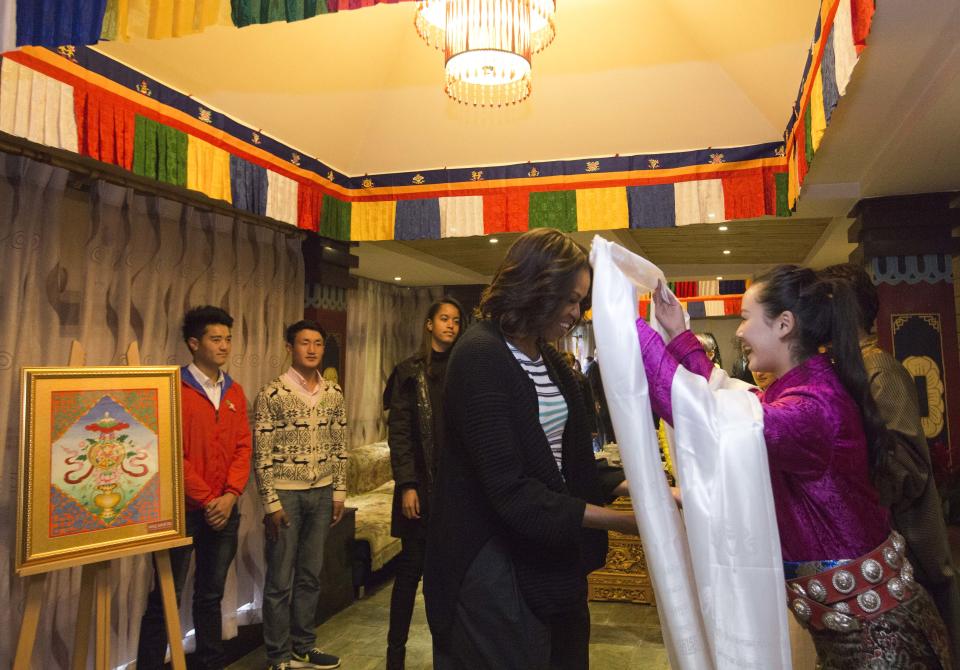 U.S. first lady Michelle Obama, center, receives a Tibetan scarf as she and her daughters Sasha, Malia, and mother Marian Robinson arrive to a Tibetan restaurant for lunch in Chengdu in southwest China's Sichuan province Wednesday, March 26, 2014. (AP Photo/Andy Wong, Pool)