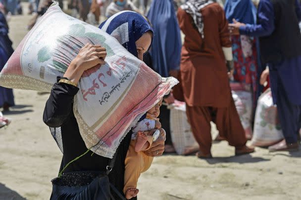 PHOTO: A woman carries her child and a sack of rice distributed to people in need by the Afghan Ministry of Refugees in cooperation with China, in Kabul on June 8, 2022. (Ahmad Sahel Arman/AFP via Getty Images, FILE)