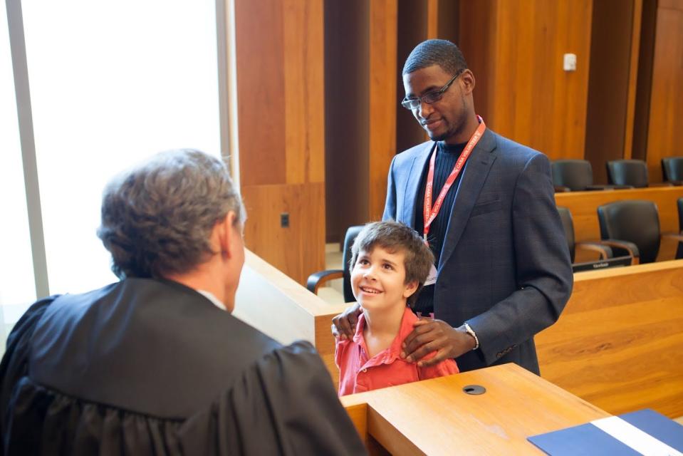 A Court Appointed Special Advocate (CASA) volunteer accompanies a child who is speaking with a judge. Courtesy of Texas CASA