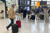 Travellers at Heathrow airport, in London, Wednesday, July 13, 2022. Heathrow Airport has introduced a cap on passenger numbers this summer as the aviation sector struggles to cope with demand for travel. No more than 100,000 daily passengers will be able to depart from July 12 until Sept. 11, the west London airport announced. (AP Photo/Alberto Pezzali)