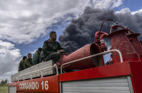 Firefighters move in a truck inside the Matanzas supertanker base to douse a fire that started during a thunderstorm, in Matanzas, Cuba, Sunday, Aug. 7, 2022. Cuban authorities say lightning struck a crude oil storage tank at the base, sparking a fire that sparked four explosions that injured more than 121 people, one person dead and 17 missing. (AP Photo/Ramon Espinosa)