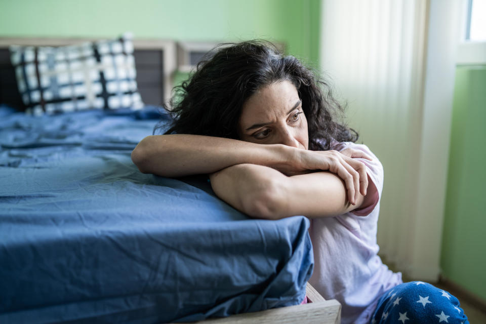 a sad woman at the edge of the bed