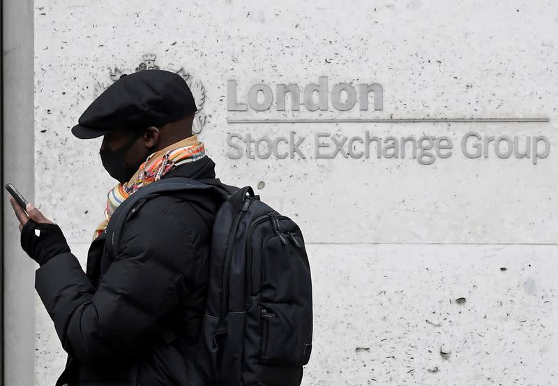 FILE PHOTO: A man wearing a protective face mask walks past the London Stock Exchange Group building in the City of London financial district, whilst British stocks tumble as investors fear that the coronavirus outbreak could stall the global economy, in L