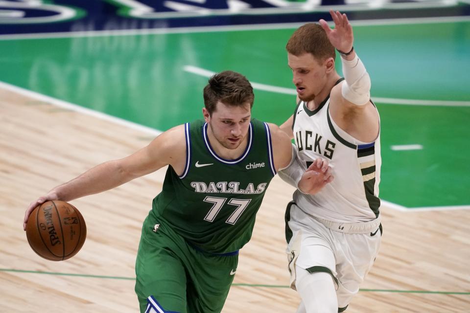 Dallas Mavericks guard Luka Doncic (77) advances the ball as Milwaukee Bucks guard Donte DiVincenzo (0) defends in the second half of an NBA basketball game in Dallas, Thursday, April 8, 2021. (AP Photo/Tony Gutierrez)