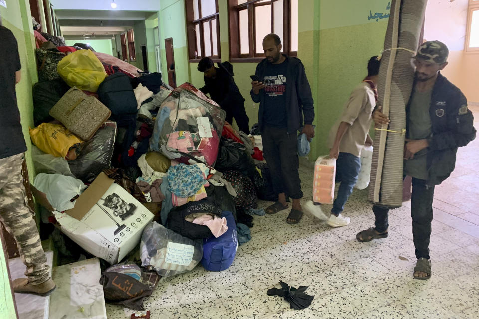 People deliver donated clothes to a flash flood-destroyed city of Derna, Libya, Saturday, Sept. 16, 2023. The death toll in Libya's coastal city of Derna has soared to over ten thousand as search efforts continue following a massive flood fed by the breaching of two dams in heavy rains, the Libyan Red Crescent. (AP Photo/Yousef Murad)