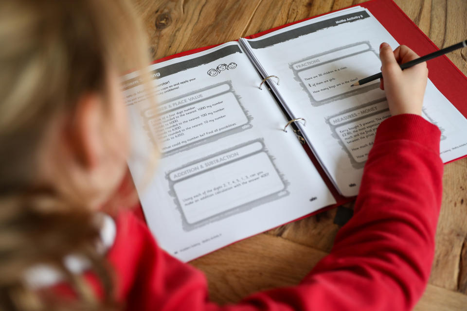 A nine year old school girl studies her homework folder following the final day of school following the Government announcement that all schools in England will close on Friday due to the Coronavirus pandemic.