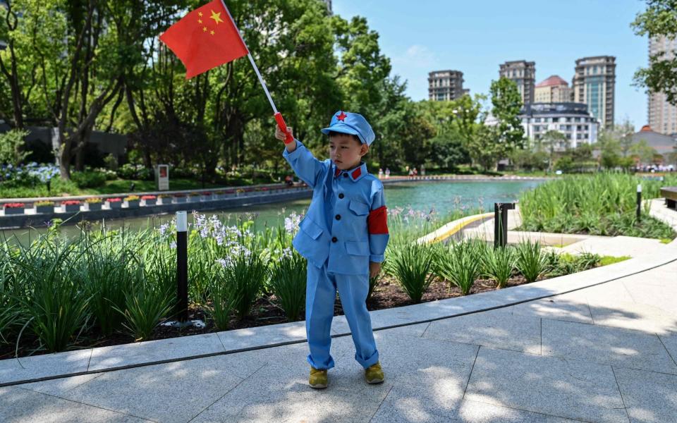 A child holds a Chinese flag near the museum of the First National Congress of the Chinese Communist Party - HECTOR RETAMAL/AFP via Getty Images