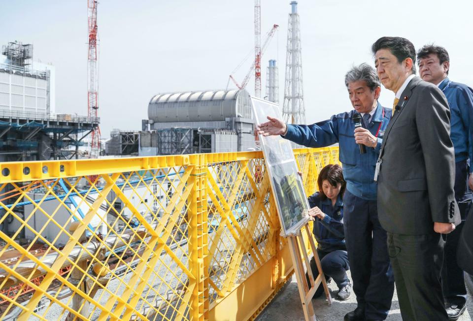 Japanese Prime Minister Shinzo Abe, foreground, visits Fukushima Dai-ichi nuclear power plant in Okuma, Fukushima prefecture, Japan, Sunday, April 14, 2019, to inspect the reconstruction effort following the tsunami, quake and nuclear accident in 2011. (Kyodo News via AP)