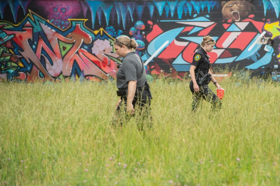 An officer carries a sharps collector as police investigate a body that was found in a creekÂ in a wooded area off the 400 block of Depot Street May 16, 2022.