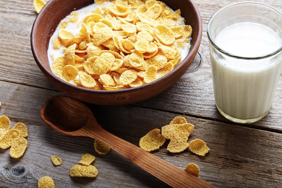 Bowl of cereal with wooden spoon on a table.