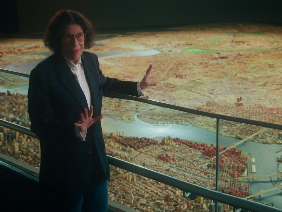 Fran Lebowitz standing in front of map of new york city on pretend its a city