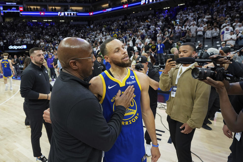 Sacramento Kings-coach Mike Brown, links, praat met Golden State Warriors-bewaker Stephen Curry na een NBA-basketbal play-in-toernooiwedstrijd op dinsdag 16 april 2024 in Sacramento, Californië. De Kings wonnen met 118-94.  (AP Foto/Godofredo A. Vásquez)