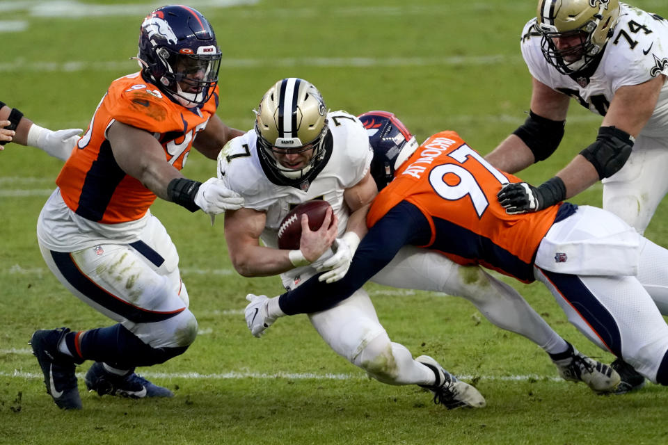New Orleans Saints quarterback Taysom Hill (7) is tackled by Denver Broncos outside linebacker Jeremiah Attaochu (97) and defensive end Dre'Mont Jones during the second half of an NFL football game, Sunday, Nov. 29, 2020, in Denver. (AP Photo/Jack Dempsey)