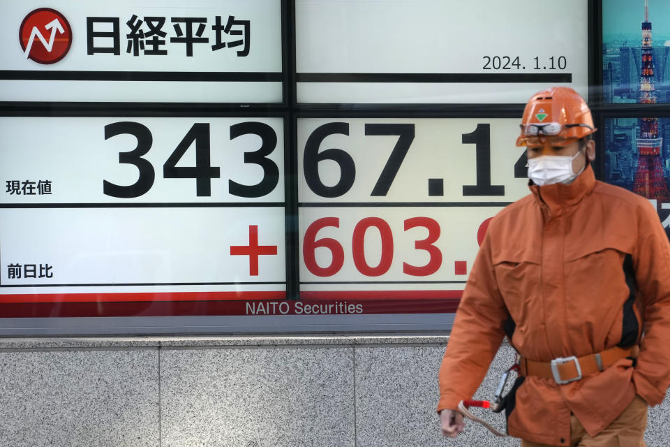 A worker walks past an electronic stock board showing Japan's Nikkei 225 index at a securities firm Wednesday, Jan. 10, 2024 in Tokyo. (AP Photo/Shuji Kajiyama)