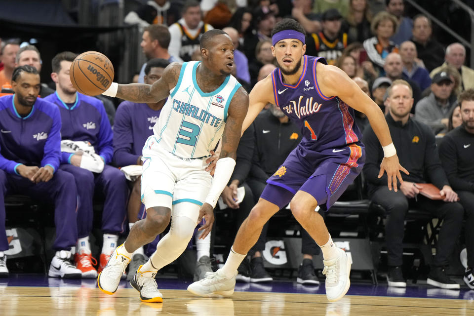 Charlotte Hornets guard Terry Rozier (3) drives on Phoenix Suns guard Devin Booker during the first half of an NBA basketball game, Friday, Dec. 29 2023, in Phoenix. (AP Photo/Rick Scuteri)