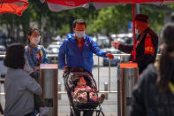 A security guard wearing a face mask takes the temperature of visitors as they enter a public park in Beijing, Saturday, April 30, 2022, the first day of the Labor Day holiday period in China. (AP Photo/Mark Schiefelbein)