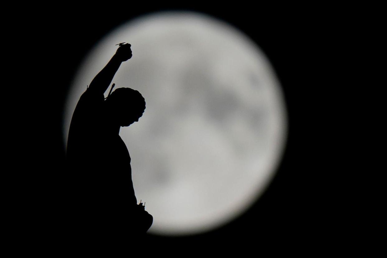 The August Super Blue Moon sets behind a spire of the Duomo gothic cathedral in Milan, Italy, Wednesday, Aug. 30, 2023. The cosmic curtain rises Wednesday night with the second full moon of the month, the reason it is considered blue. It is dubbed a supermoon because it is closer to Earth than usual, appearing especially big and bright.(AP Photo/Luca Bruno)