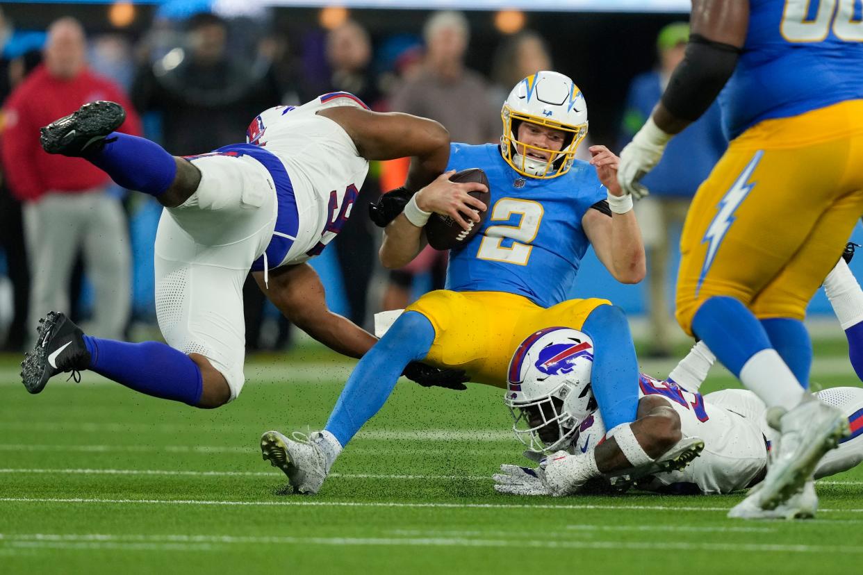 Los Angeles Chargers quarterback Easton Stick (2) is tackled by a pair of Buffalo Bills defenders during the second half of an NFL football game Saturday, Dec. 23, 2023, in Inglewood, Calif. (AP Photo/Ryan Sun)