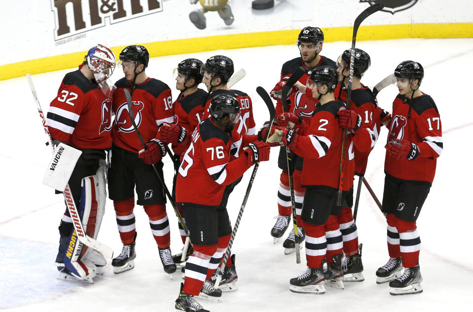 New Jersey Devils goaltender Jon Gillies (32) celebrates with teammates after defeating the Carolina Hurricanes in an NHL hockey game Saturday, Jan. 22, 2022, in Newark, N.J. (AP Photo/Noah K. Murray)