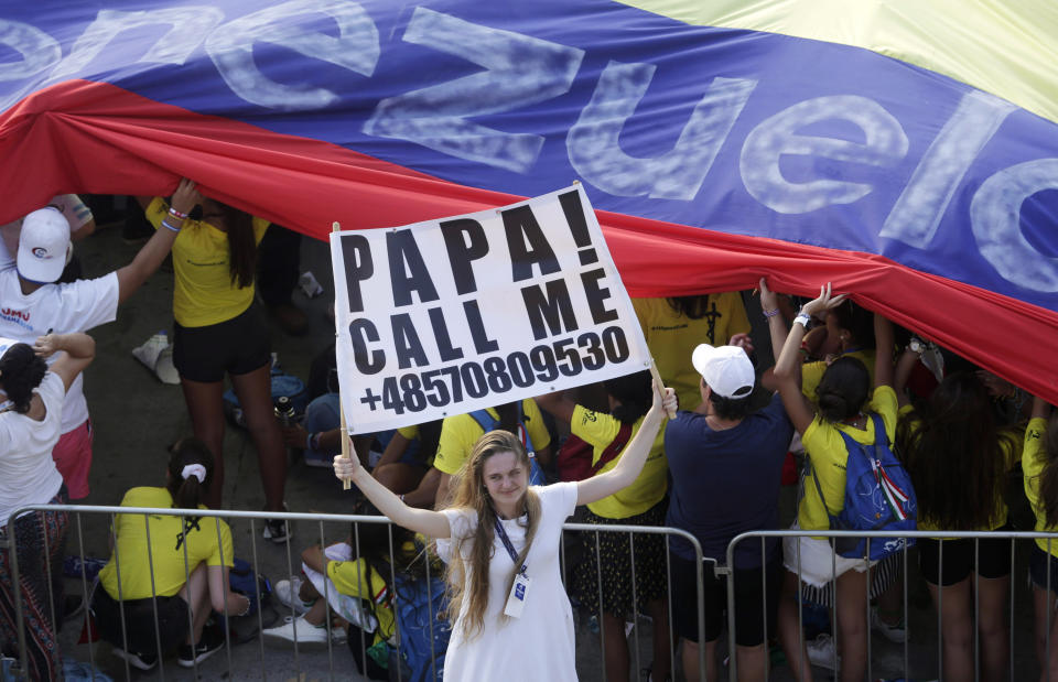 A pilgrim holds a sign asking Pope Francis to call her as she waits for him to arrive to celebrate an outdoor Mass in Panama City, Thursday, Jan. 24, 2019. Pope Francis has arrived in Panama amid a political crisis in nearby Venezuela, a migration standoff over the proposed U.S.-Mexico border wall and tens of thousands of wildly excited young Central Americans welcoming him. (AP Photo/Arnulfo Franco)