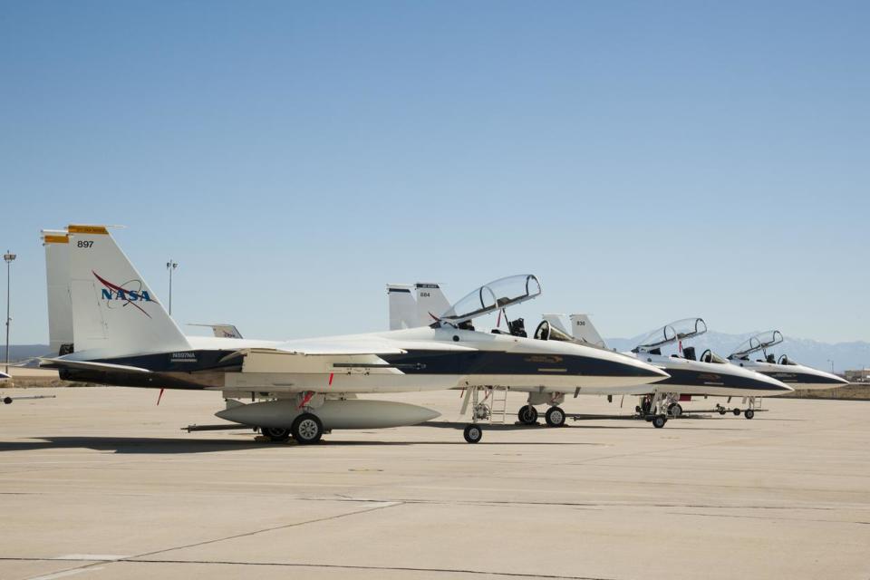 three white fighter jets on a desert runway