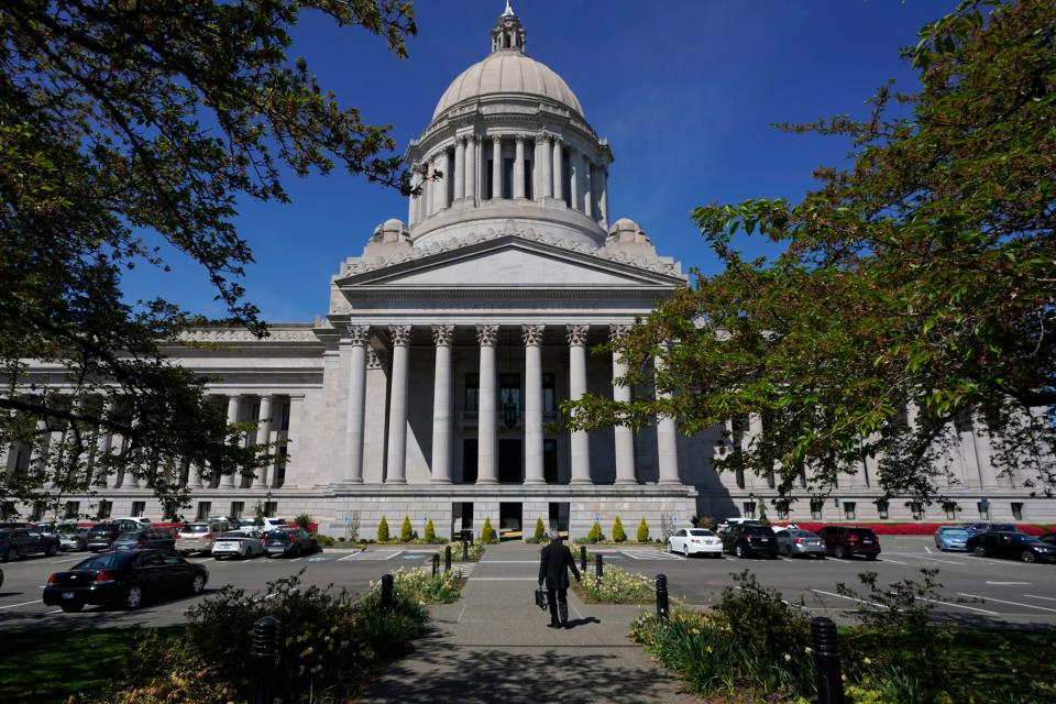 FILE — A person walks near the Legislative Building in April 2021 at the Capitol in Olympia.