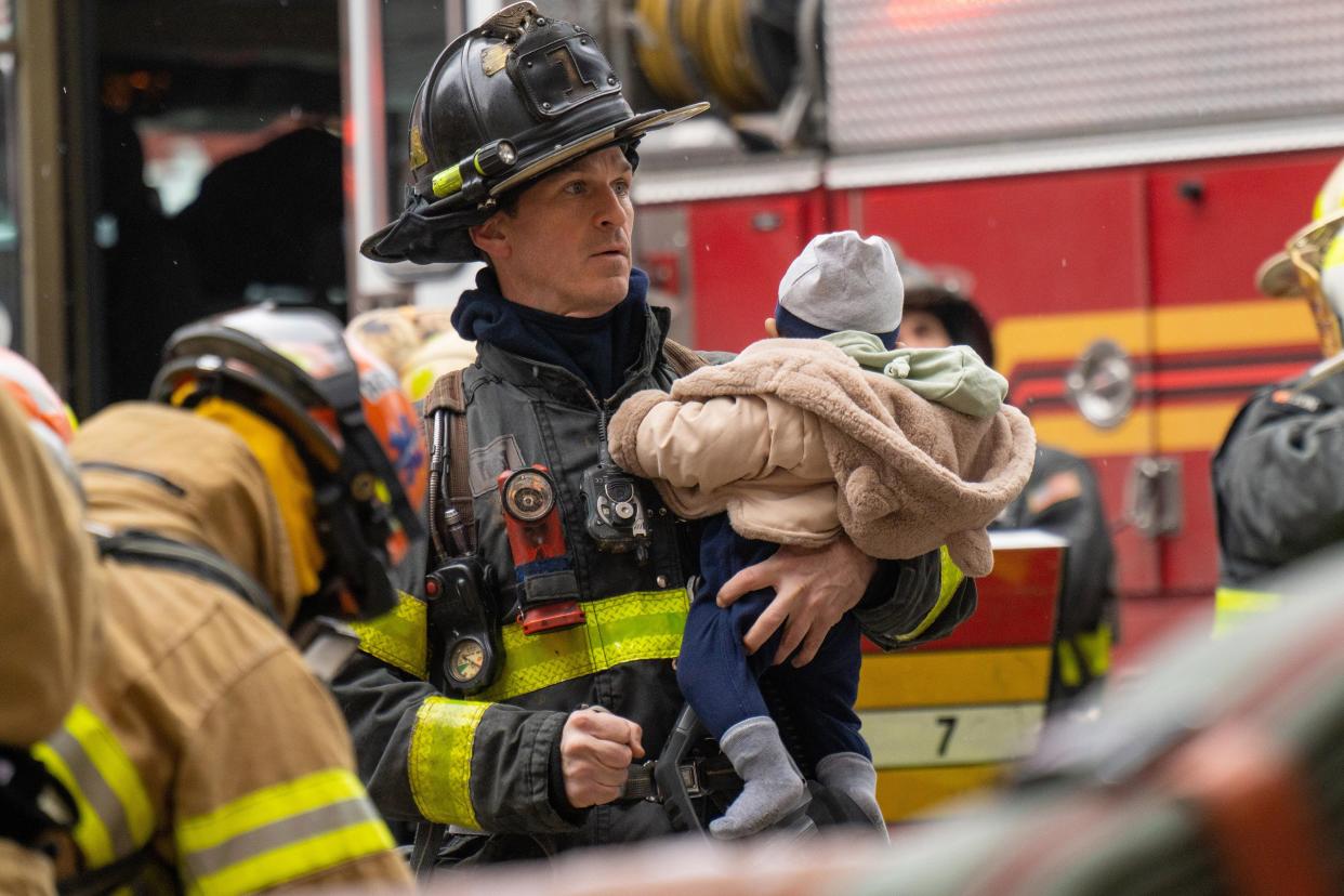 A Firefighter carries a rescued baby during a massive fire in an apartment building in the Bronx on Sunday, Jan. 9, 2022.