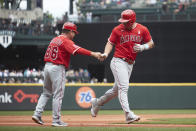 Los Angeles Angels' Mike Trout, right, is greeted by third base coach Mike Gallego after hitting a two-run home run off a pitch from Seattle Mariners starting pitcher Logan Gilbert during the fourth inning of a baseball game Sunday, June 19, 2022, in Seattle. (AP Photo/John Froschauer)