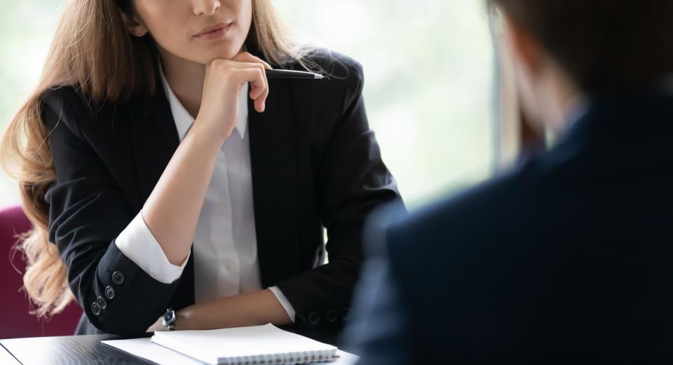 A woman in a suit attentively listens to a man during a professional meeting at a table. Names not provided