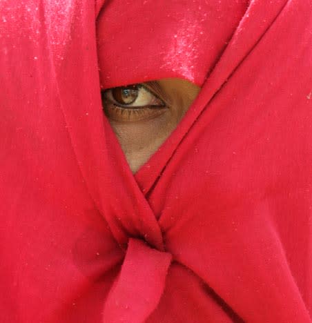 A relative of a member of the Gujjar community, a lower caste, who was killed when shots were filed by police looks on near the dead body, unseen, at Bayana town in the Bharatpur district of Rajasthan state, India, Thursday, May 29, 2008. Gujjars blocked major roads, burned car tires, and threw stones at police in several areas around New Delhi on Thursday in a continuation of protests in the country's north and west that left 39 people dead. Members of the Gujjar tribe threatened to shut down the capital unless the government agreed to reclassify them as members of the lowest caste so that they can benefit from government quotas. (AP Photo/Aman Sharma)