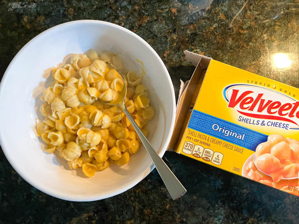 Cooked Velveeta mac 'n' cheese in a bowl, next to its packaging