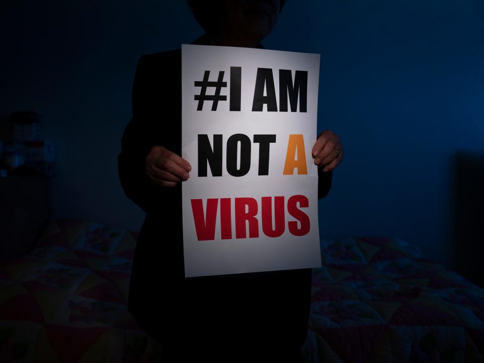 A sign in black, yellow, and red reads "# I am not a virus"