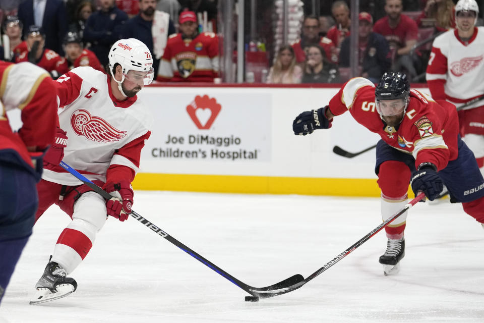 Detroit Red Wings center Dylan Larkin (71) attempts a shot as Florida Panthers defenseman Aaron Ekblad (5) defends during the first period of an NHL hockey game Thursday, Dec. 8, 2022, in Sunrise, Fla. (AP Photo/Lynne Sladky)