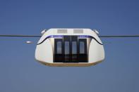 A small, four-seat pod made by uSky glides above the sands of a test track in Sharjah, United Arab Emirates, Thursday, Oct. 28, 2021. The futuristic transit solution is being promoted by a Belarusian firm that hopes to secure contracts here in the near future. However, uSky has ties back to a Belarusian investment firm called SkyWay that has seen multiple nations in Europe and elsewhere issue warnings to investors that they "may be involved in a scam." (AP Photo/Jon Gambrell)