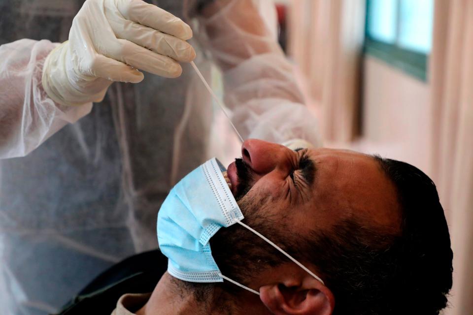 A health worker takes a swab sample to test for Covid-19 in the West Bank village of DuraAFP via Getty