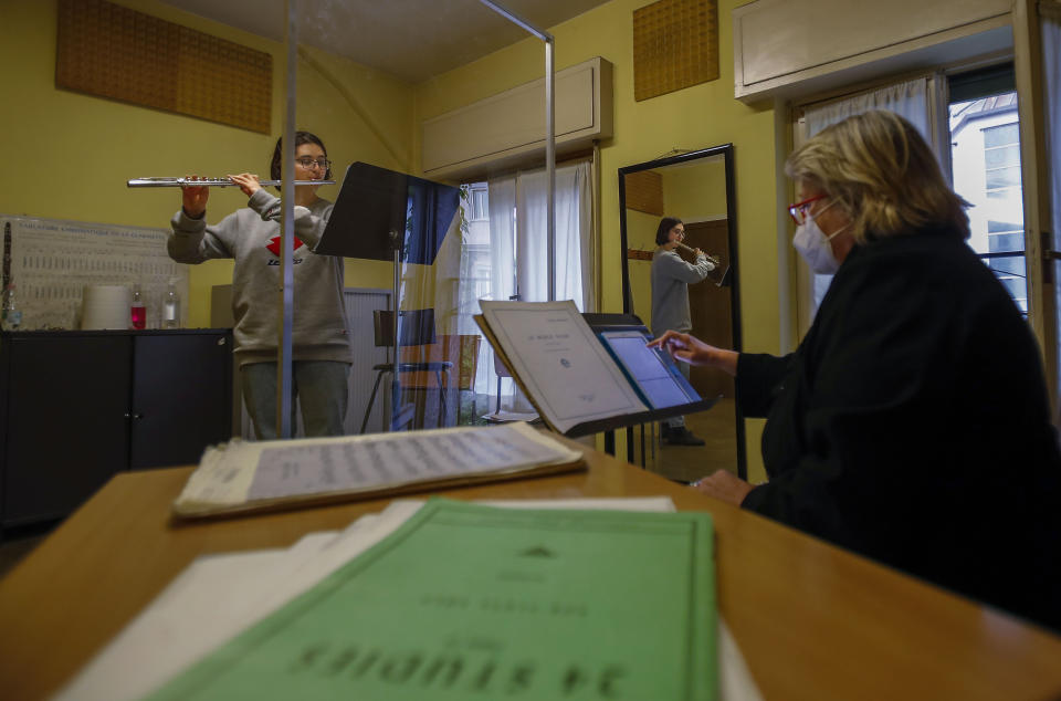 Linda Facchinetti plays her flute behind a transparent panel to curb the spread of COVID-19, during a lesson with maestro Rosalba Montrucchio at the Giuseppe Verdi Music Conservatory, in Milan, Italy, Thursday, April 29, 2021. Whatever the instrument, flute, violin or drums, students at Italy's oldest and largest music conservatory have been playing behind plexiglass screens during much of the pandemic as the Conservatory found ways to preserve instruction throughout Italy’s many rolling lockdowns. (AP Photo/Antonio Calanni)