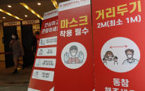 A woman wearing a face mask walks near banners showing precautions against the coronavirus at an exhibition hall of K-Hospital Fair in Seoul, South Korea, Wednesday, Oct. 21, 2020. (AP Photo/Lee Jin-man)