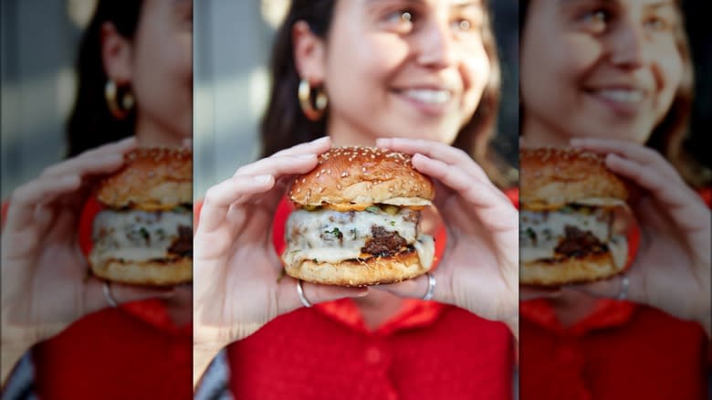 woman holding cheesy burger