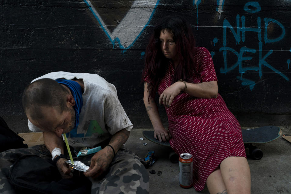 Jenn Bennett, who is high on fentanyl, sits on her skateboard with a visible black eye as her friend, Jesse Williams, smokes the drug in Los Angeles, Tuesday, Aug. 9, 2022. Use of fentanyl, a powerful synthetic opioid that is cheap to produce and is often sold as is or laced in other drugs, has exploded. Because it's 50 times more potent than heroin, even a small dose can be fatal. It has quickly become the deadliest drug in the nation, according to the Drug Enforcement Administration. Two-thirds of the 107,000 overdose deaths in 2021 were attributed to synthetic opioids like fentanyl, the U.S. Centers for Disease Control and Prevention says. (AP Photo/Jae C. Hong)