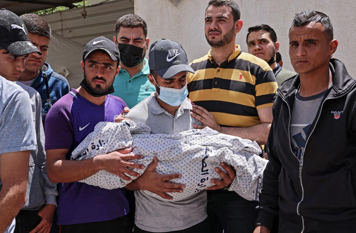 The father of Hur Alzamly, a child killed in an Israeli air strike, carries her shrouded body away from a hospital morgue, before her burial in Rafah in the southern Gaza Strip, on Friday. 