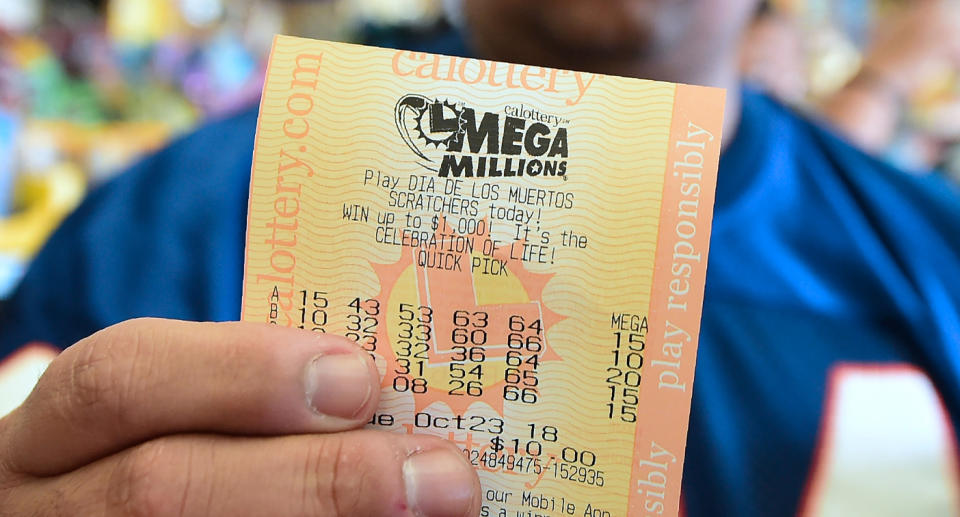 Photo shows a man holding a Mega Millions lotto ticket.