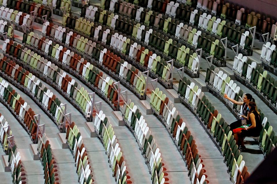 People sit in the empty stadium before the opening ceremony for the Tokyo 2020 Olympic Summer Games at Olympic Stadium on July 23, 2021.