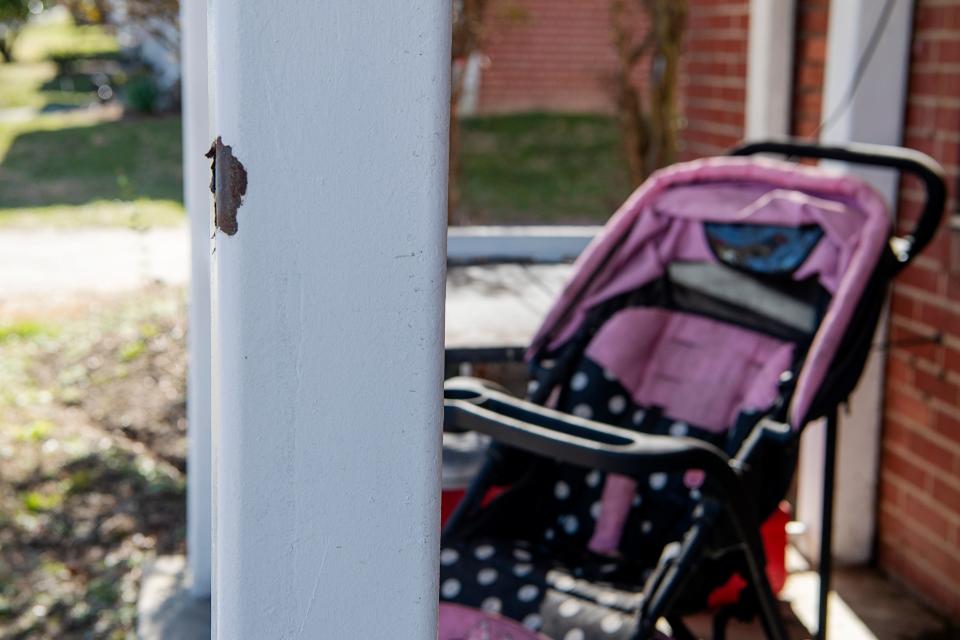 Paint is chipped from a porch post next to a child’s stroller at Hillcrest Apartments, February 15, 2024. A neighbor said the post was struck by a bullet, causing the chipping.